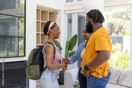 Foto African American family greeting teenage daughter holding green-black backpack i