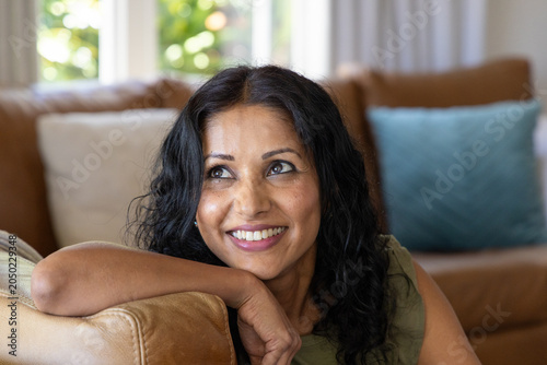 Принти на полотні Middle-aged woman reclining on leather armrest in olive-green top with teal pill