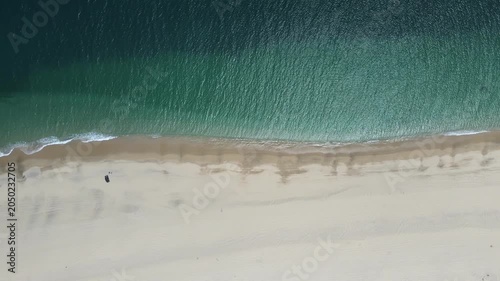 Overhead drone footage capturing the meeting point between crystal-clear turquoise waters and white sand beach at Punta Arena, Baja California Sur, Mexico.