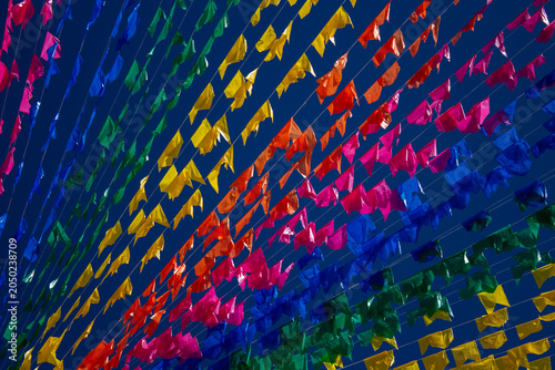 Detalhe em close de bandeirolas coloridas de Festa Junina balançando ao vento