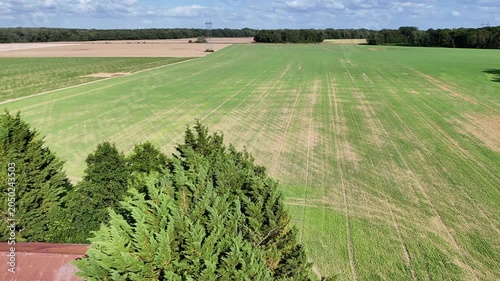 Vue aérienne de vastes champs céréaliers en Seine-et-Marne sous un ciel nuageux avec rayons de soleil