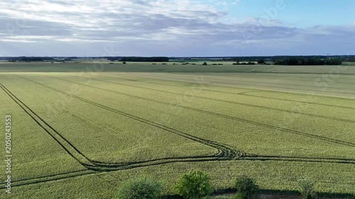 Vue aérienne de vastes champs céréaliers en Seine-et-Marne sous un ciel nuageux avec rayons de soleil