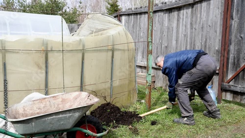 A gardener plants a bush in a garden bed in a park. A gardener plants a plant in a garden plot.