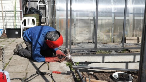 A specialist welds a metal structure for a frame. A welder welds a metal structure.