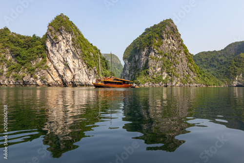 Photos Traditional tourist boat floating on calm water with a perfect reflection of lim