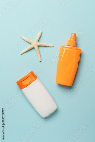 Sunscreen, sun cream and sunglasses on blue background.