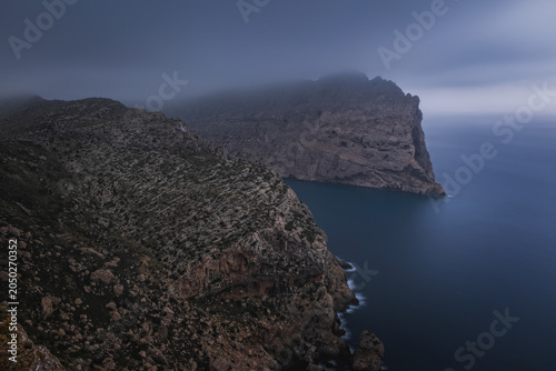 View from the Mirador Es Colomer towards the island Colomer and the mountain range on Formentor peninsula, cloudy sunrise. Mallorca, Spain, October 2024. Long exposure picture