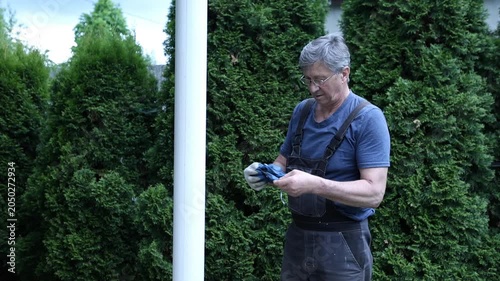 A construction worker uses a power tool to strip paint from a pole.