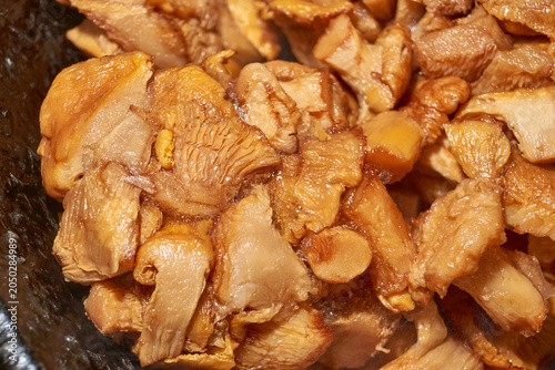 Boiled chanterelle mushrooms thawing in a frying pan with visible steam. Home cooking process for preparing mushroom filling for tartlets, pies, appetizers, and hot dishes.