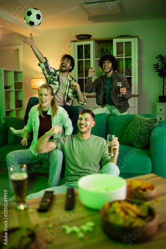 Friends celebrating soccer goal watching match at home
