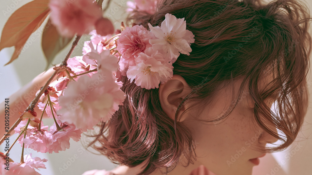 Naklejka premium Close-up portrait of woman with natural makeup and pink cherry blossoms