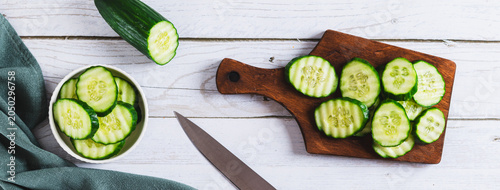 Foto Slices of homegrown fresh cucumbers on a board and dill on a table top view web