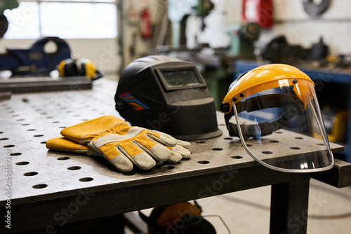Foto Welding safety gear including helmet, gloves, and face shield on a workbench