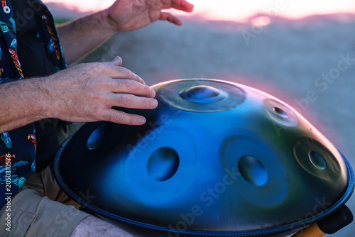 Картината върху платно Human hands playing a handpan or pantam, creating melodic sounds outdoors during