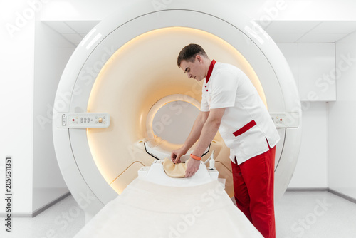 Quadro su tela Radiology technologist preparing head coil on MRI scanner table in modern hospit