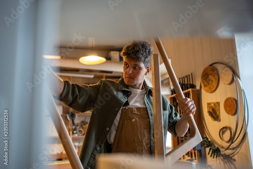 Cuadro en lienzo Carpenter inspects table parts legs with ruler for flatness and quality in woodworking workshop