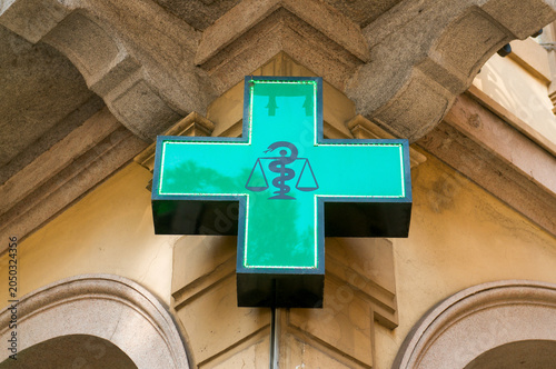 Green pharmacy cross sign on a historic building facade in Lugano Switzerland