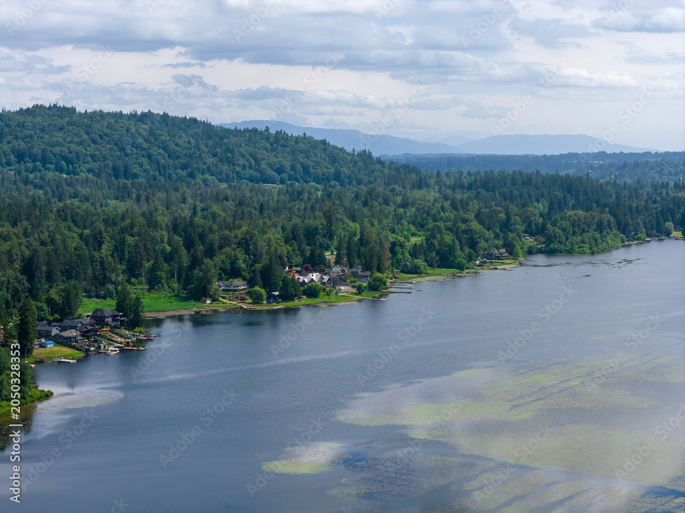 Fototapeta premium Aerial View Of Forested Hills And Waterfront Homes Along A Calm Lake Near Mission BC Canada