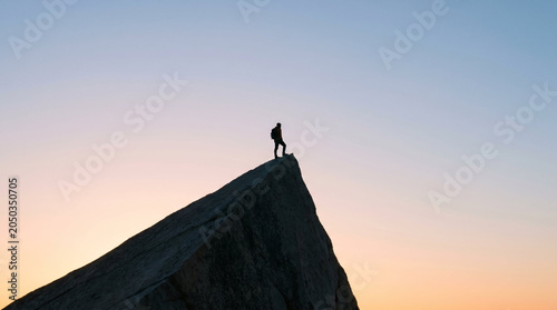 Lone explorer with reflective mood standing on sharp peak representing accomplishment against vast twilight sky with copy space