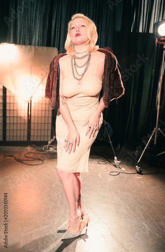 The glamorous woman showcases a beautiful shimmering dress while adorned in luxurious jewelry, creating a magnificent visual with soft lighting that amplifies her presence.