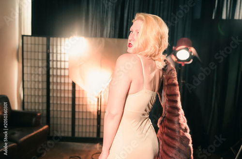 This image showcases an elegant model with stylish blonde hair, capturing a timeless vintage aesthetic while posing in a glamorous outfit, highlighting fashion and beauty.