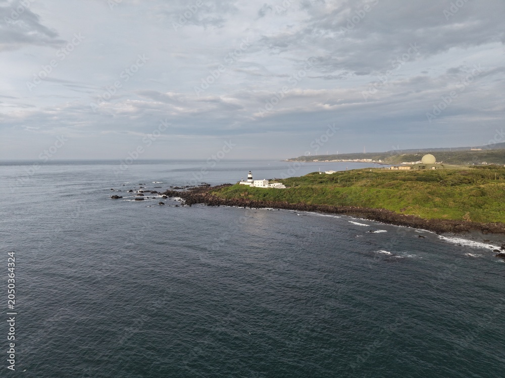 Fototapeta premium Aerial view of a lighthouse on a rocky coastal cape.