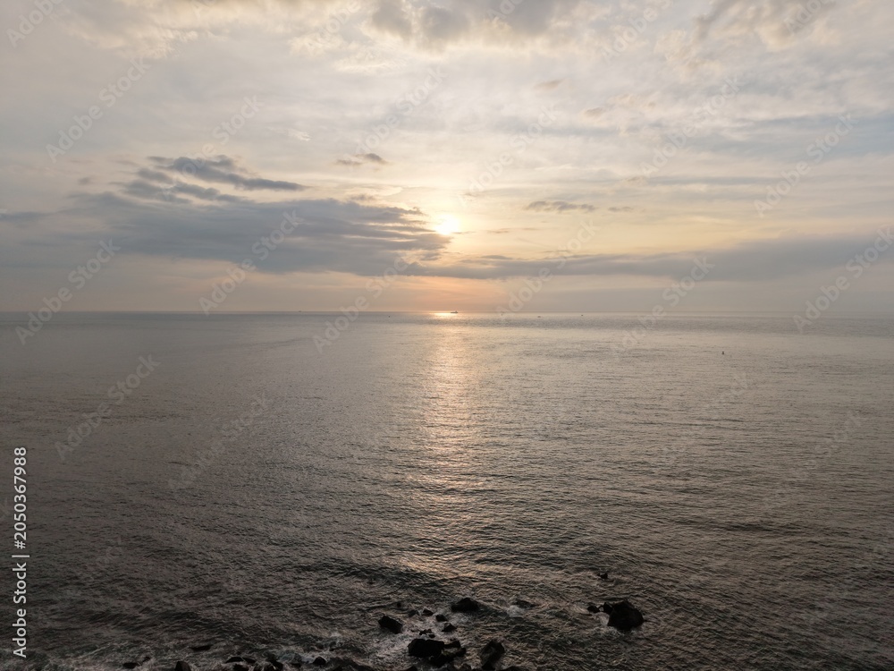 Obraz premium Aerial seascape with a sunset reflecting on the calm ocean.
