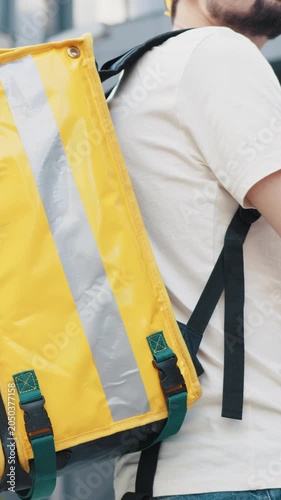 A person with a yellow delivery backpack, ready to deliver food or other items.