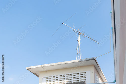 Television antenna mounted rooftop against clear blue sky highlighting broadcasting communication technology residential infrastructure
