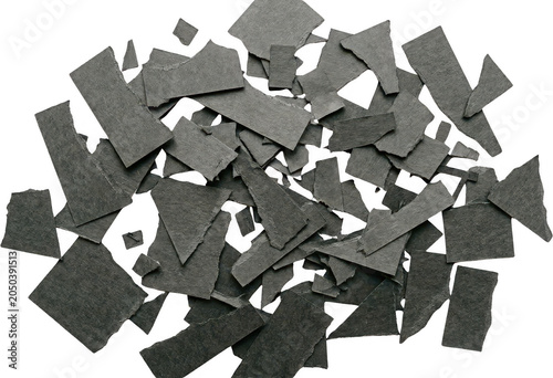 A pile of torn dark grey paper fragments and scraps scattered randomly creating a textured abstract composition with rough edges paper scraps torn paper dark paper material