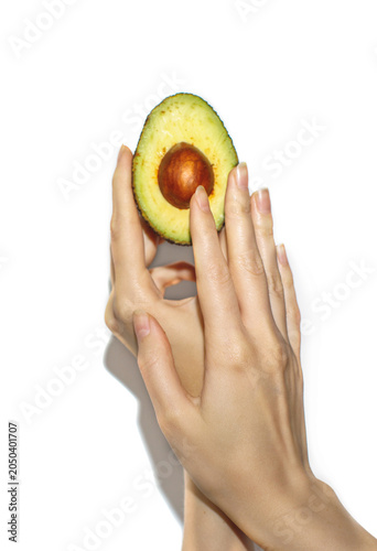 Female hand holding half avocado isolated on white background. Healthy food concept with copy space.