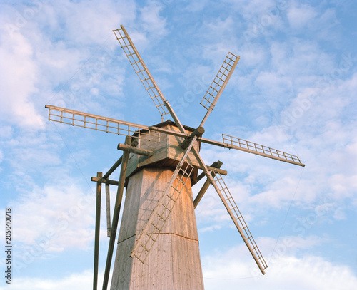 Traditional windmill tower against blue sky with clouds. Historic rural architecture and cultural heritage landmark.