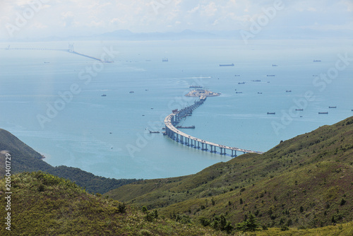 View of Hong Kong coastal infrastructure with shipping routes, cargo vessels and bridge construction. Global trade, logistics and maritime industry concept.