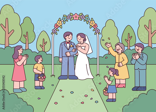 Outdoor wedding ceremony with bride, groom, family, and flower girls in a garden setting.