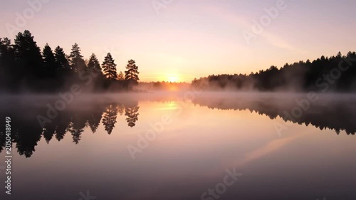 Serene Sunrise Over Misty Lake with Forest Reflection.