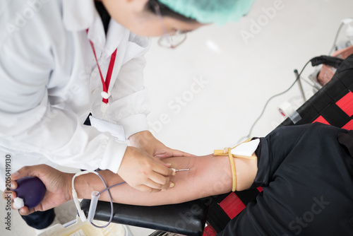 Selective focus hand of doctor inject blood from donor arm into bag while donating blood at blood bank unit in hospital.Donation for emergency surgery at donation center.Save life and medical concept.