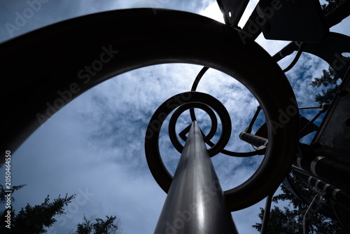 Metal spiral structure in playground against dramatic sky