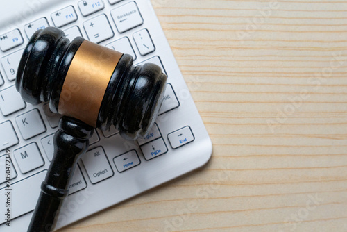 A wooden gavel on a white computer keyboard. Cyber law, digital regulations, internet crime, online auctions, and e-commerce legislation concept. Copy space for text.