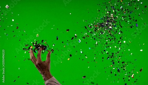 Hand throwing colorful confetti against a green backdrop