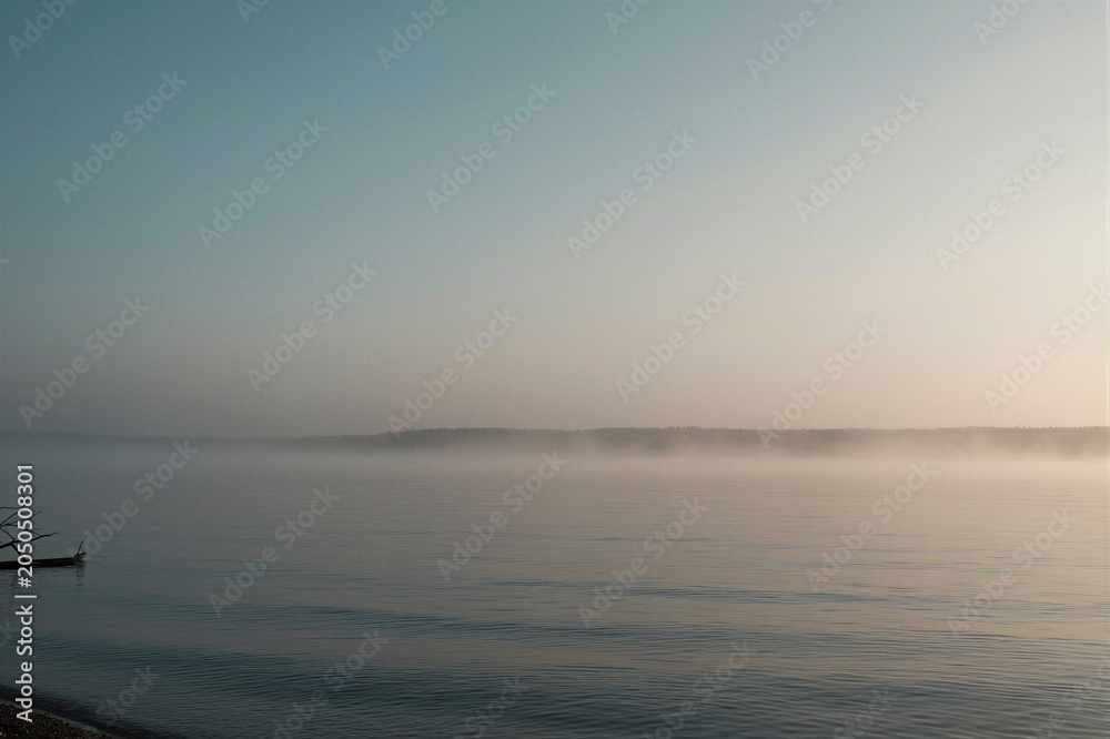 Obraz premium A weathered wooden boat rests on the serene lakeshore of Mecklenburg-Vorpommern, Germany, shrouded in morning fog.
