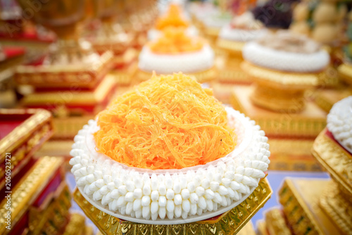 Thai dessert golden thread sweet traditional ceremony offering wedding tray garland on ornate pedestal, bright orange strands with jasmine flowers, festive cultural food for celebration