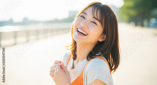 日差しを浴びながら弾ける笑顔をみせる女性