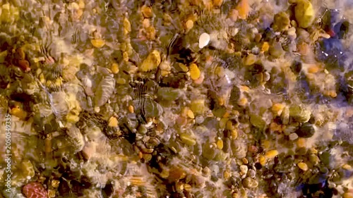 Slow motion of water flowing above the golden brown rocks
