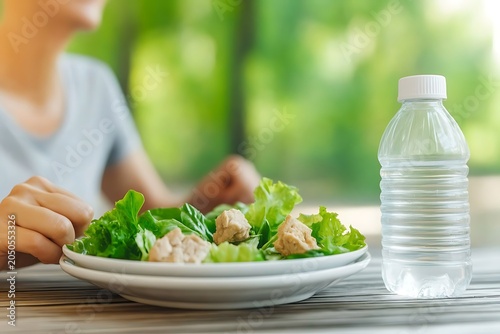 Childholds fork and eats salad with chicken at outdoor table during sunny day