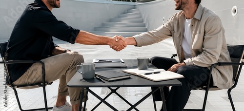 Two businessmen shaking hands at outdoor meeting