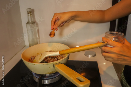 Foto Hands Adding Spice To Sauteing Food On Stovetop.