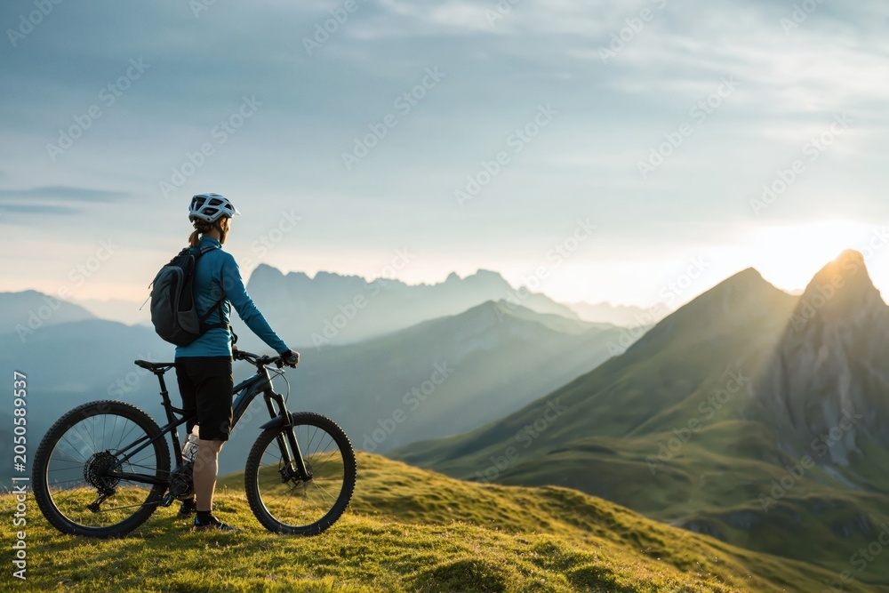 Fototapeta premium Biker cycling adventure on dolomites mountain ridge at golden sunset italy