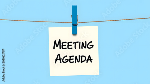 A meeting agenda note hanging on a string with a blue background