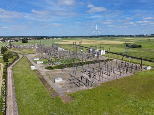 Petite centrale électrique rurale en Meurthe-et-Moselle. Vue aérienne panoramique des installations électriques, transformateurs, pylônes, câbles, répartiteurs. Au milieu des champs et des cultures.
