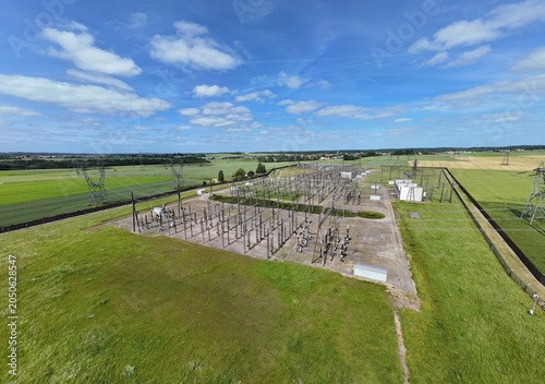 Petite centrale électrique rurale en Meurthe-et-Moselle. Vue aérienne panoramique des installations électriques, transformateurs, pylônes, câbles, répartiteurs. Au milieu des champs et des cultures.